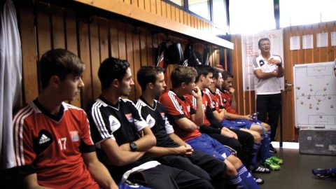 Mannschaft in der Kabine hört dem Trainer zu Mannschaft in der Kabine hört dem Trainer zu